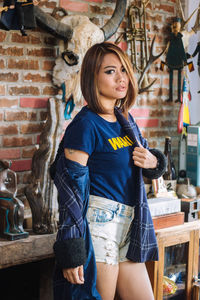 Portrait of young woman standing against wall