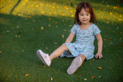 Full length of cute girl sitting on grass at park