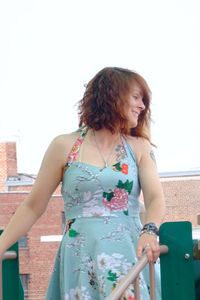 Young woman looking down while standing against railing