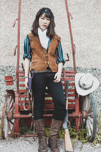 Portrait of young woman standing against wall