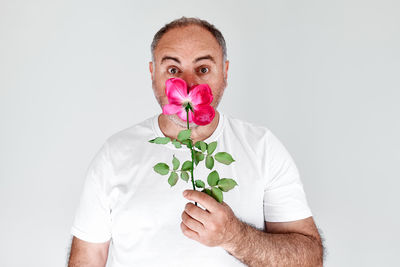 Portrait of man holding flower against white background