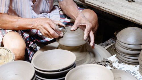 Midsection of man working on pottery wheel at workshop