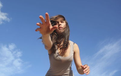 Low angle view of woman standing against blue sky