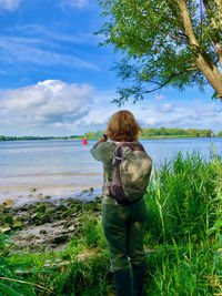 Rear view of woman standing on river bank watching over water