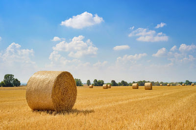 Hay bales on field against sky