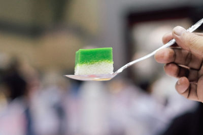 Close-up of hand holding sweet food in spoon