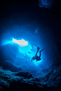 Low angle view of scuba divers swimming in cave