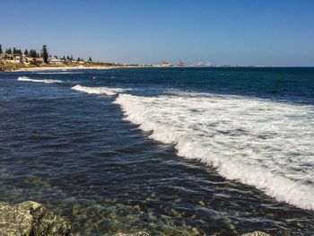 Scenic view of sea waves rushing towards shore against clear blue sky