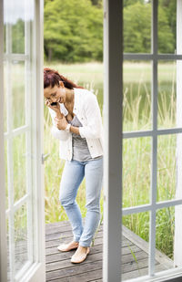 Happy woman talking on mobile phone at summer house