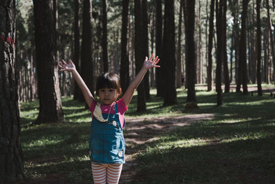 Portrait of girl with arms raised standing in forest