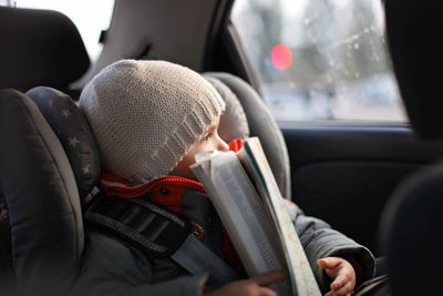 Boy looking though window while sitting in car