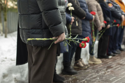 Flowers in old man's hand at funeral. details of funeral ceremony. commemorative flowers. 