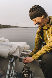 Smiling woman using camping stove on boat