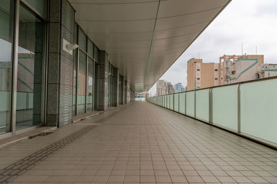Empty footpath amidst buildings in city