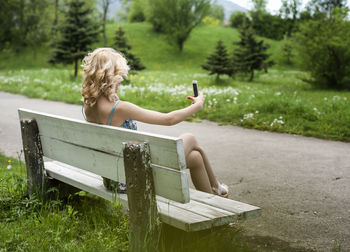 Rear view of woman sitting on bench in park