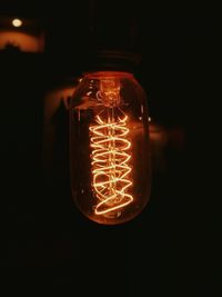 Close-up of illuminated light bulb against black background