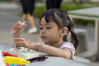 Close-up of cute girl playing with childs play clay at table outdoors