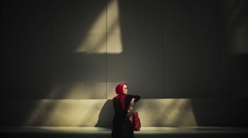 Rear view of woman standing against wall