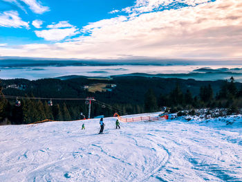 People skiing on snowcapped mountain against sky