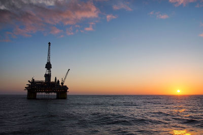 Silhouette ship in sea against sky during sunset