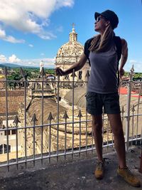 Full length of woman standing by railing against sky in city