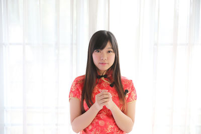 Portrait of beautiful young woman standing against wall