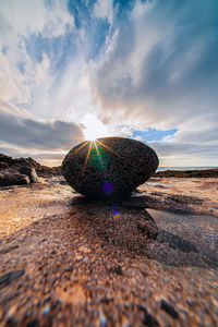 Surface level of rocks at beach against sky during sunset