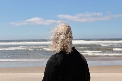 Rear view of woman on beach against sky