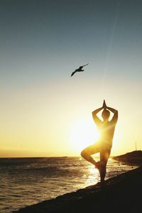 Silhouette of man on beach against sky during sunset