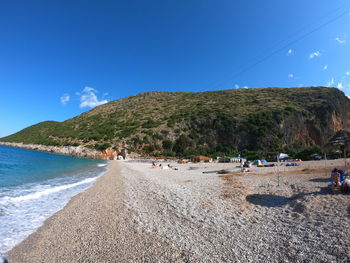 People on beach by mountain against sky