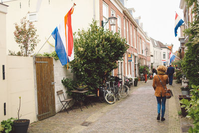 Rear view of woman walking amidst dutch flags on buildings