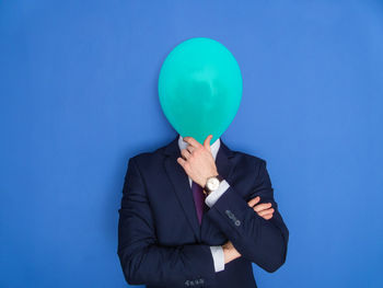 Man holding balloons against blue background