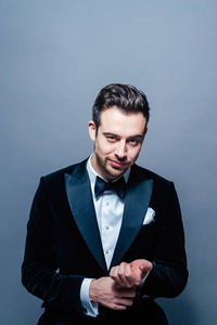 Portrait of young man standing against gray background