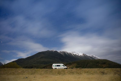 A motorhome park at the campsite in new zealand during night with snowcapped mountain in background.