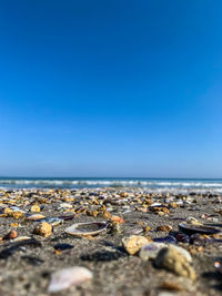 Surface level of pebble beach against clear blue sky