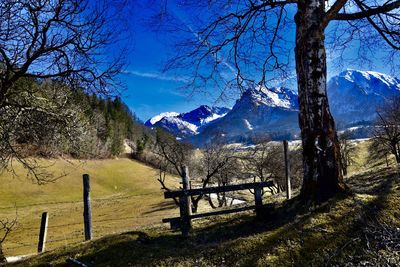 Bench on field against snow covered mountains and sky