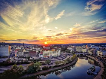 High angle view of river amidst buildings against sky during sunset
