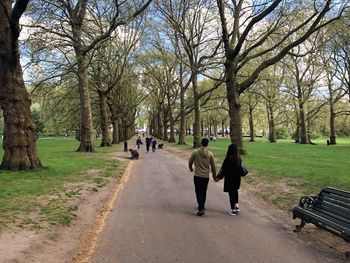Rear view of people walking on footpath in park