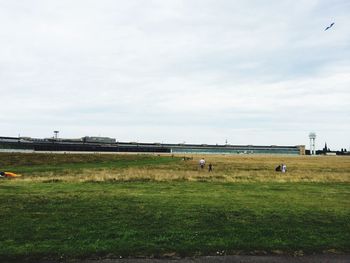 View of grassy field against cloudy sky