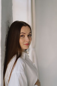 Cute young pregnant girl sitting on the white studio in warm light