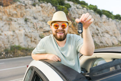 Portrait of young man wearing sunglasses against car