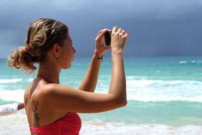 Rear view of woman at beach against sky