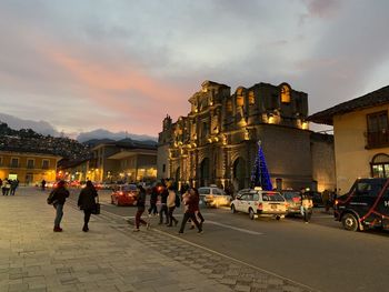 People on street amidst buildings in city against sky