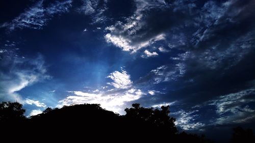 Low angle view of silhouette trees against sky