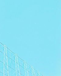 Low angle view of telephone pole against clear blue sky