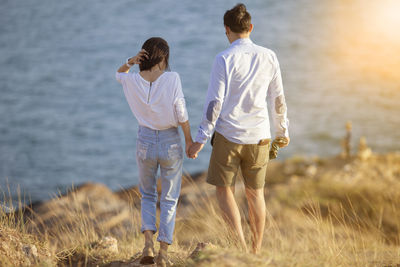 Rear view of couple walking on shore
