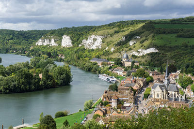 Townscape by river against cloudy sky