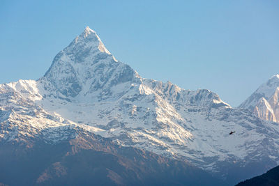 Aerial view of snowcapped mountains against clear sky