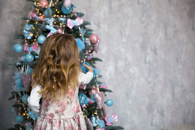 Rear view of woman standing by christmas tree