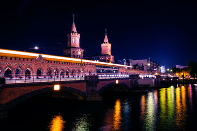 Illuminated bridge over river against sky in city at night